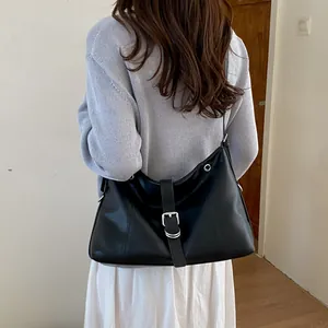 Macro view of the black leather shoulder bag with a stylish silver buckle and grommet detail.