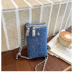 Detail of blue denim mini crossbody phone bag with silver chain and camellia charm