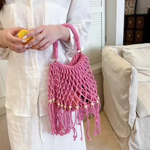 Detailed view of a pink macrame woven handbag with fringe and wooden bead accents