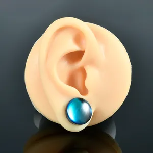 Detailed macro view of a blue gradient glass ear gauge plug on a silicone ear model