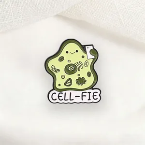 Detailed close-up view of a funny cartoon cell selfie enamel pin with CELL-FIE pun