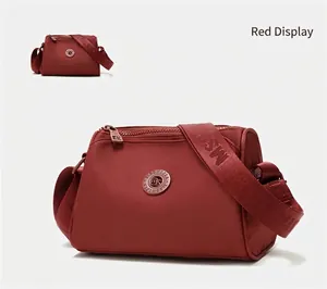 Red water-repellent nylon crossbody bag with adjustable wide logo strap in dumpling style