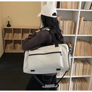 Large capacity off-white travel duffel bag shown on shoulder in library background