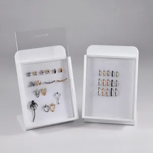 Detailed view of white acrylic jewelry display boards with lids showcasing various body jewelry.