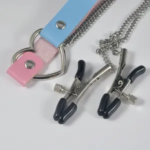 Close-up detail of heart-shaped ring choker with pink blue straps and metal nipple clamps