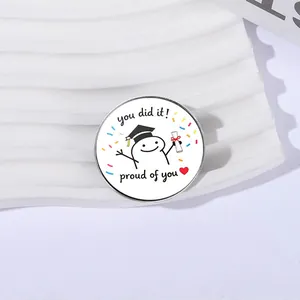Close-up of a circular graduation metal badge with cartoon scholar and proud of you text