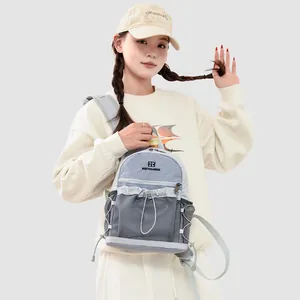 Détail frontal d'un petit sac à dos gris avec poches en filet et design à cordon sur modèle