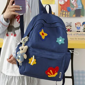 Cute blue school backpack with colorful patches and teddy bear charm for teenage girls.