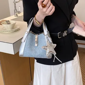 Close-up of a stylish light blue denim bucket bag with silver trim and star charm