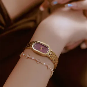 Elegante goldene Damenarmbanduhr aus Edelstahl mit weinrotem Zifferblatt am Handgelenk