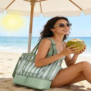 Model holding a large green striped insulated picnic cooler bag on a sunny sandy beach