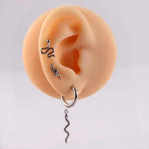 Detailed view of three silver snake-shaped stainless steel earrings on a silicone model