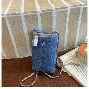 Close-up detail of a blue denim chain phone bag with sparkling studs and flower accessory