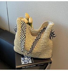 Vue détaillée du sac fourre-tout en paille avec des bretelles à rayures noires et blanches.