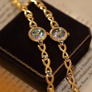 Detalle de un reloj dorado vintage con esfera de nácar colorida sobre un joyero.