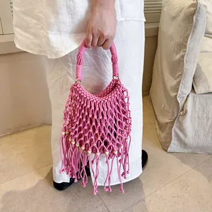 Close-up of pink macrame woven handbag with fringe and wooden bead details