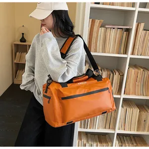 Large orange travel bag with model in lifestyle setting, showcasing size and durable material