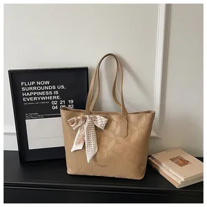 Close-up detail of beige tote bag with geometric pattern and decorative silk scarf