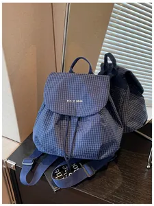 Detail of blue grid casual backpack showing drawstring closure and flap with brand name