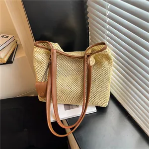 Dettaglio di una grande borsa da spiaggia intrecciata beige con manici in pelle marrone