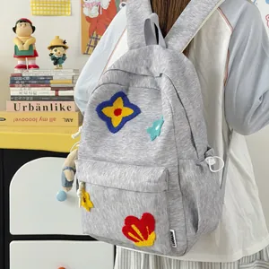 Detailed side view of a gray student backpack with cute embroidered flower patches.