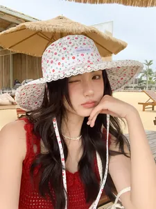 Detailed view of women's floral bucket hat with lace trim on a sunny beach