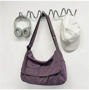 Detail view of a large purple canvas messenger bag hanging on a stylish wavy wall rack