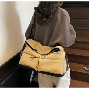 Large khaki multi-pocket crossbody gym bag shown in a stylish outdoor lifestyle setting
