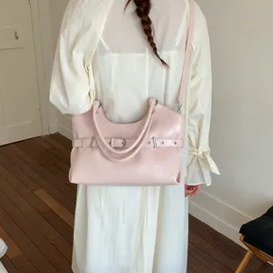 Detailed view of stylish pink tote bag featuring unique belt buckle and eyelet design on model