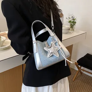 Close-up of a silver and blue stylish bucket bag with a star charm worn on the shoulder