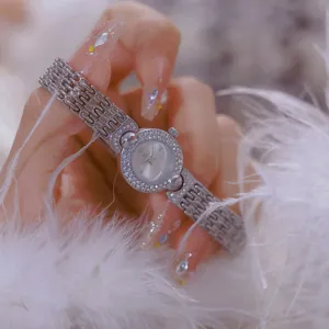Elegant close-up of a silver vintage women's watch with crystals on white feathers