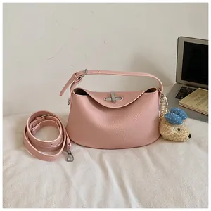 Detailed view of a pink pebbled leather bucket bag featuring a cute teddy bear charm