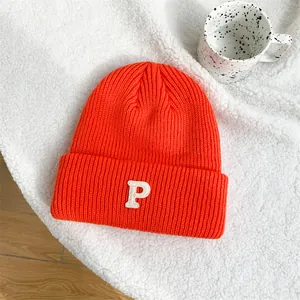 Close-up view of a vibrant orange knitted beanie featuring a white embroidered letter P on the brim