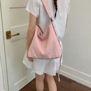 Detail of pink canvas tote bag with shiny silver stars worn by model in white dress