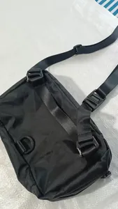 Vista trasera detallada de un bolso bandolera deportivo negro con correas y hebillas ajustables