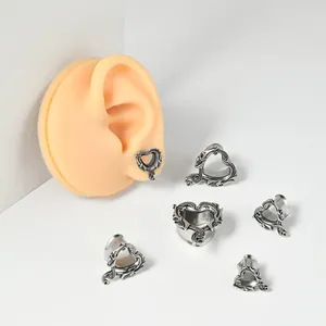 Vista de detalle de túneles de oreja de acero inoxidable en forma de corazón con calaveras