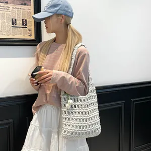 Bolso de hombro de punto calado blanco llevado por modelo para un look casual de playa