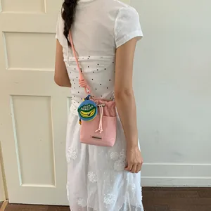 Detailed view of a stylish pink mesh drawstring bucket bag featuring a banana charm