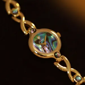Detalle de primer plano de reloj retro dorado con esfera de concha de abulón iridiscente