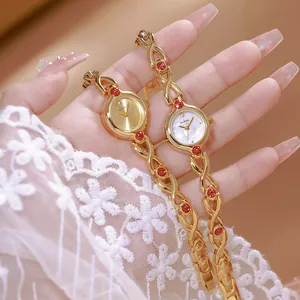Primer plano de relojes de oro vintage franceses con piedras rojas sobre fondo de encaje