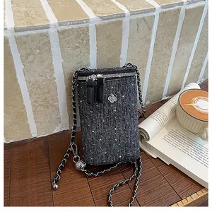 Close-up detail of black tweed phone bag with silver sequins and camellia charm accessory