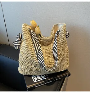 Vue détaillée d'un sac cabas en paille tressée avec poignées rayées sur un livre