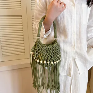 Close-up of green woven macrame handbag with long tassels and wooden beads decor.