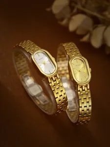 Vista detallada de dos elegantes relojes dorados ovales con brazaletes de eslabones