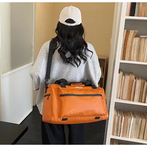 Close-up of a large orange travel duffle bag being worn by a model in a library room