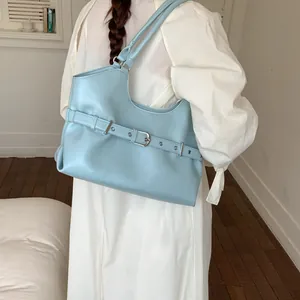 Stylish light blue faux leather tote bag with decorative belt buckle carried on shoulder