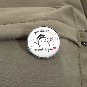 Macro view of a graduation cartoon brooch pinned on a khaki fabric surface.