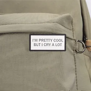 Close-up of minimalist metal brooch with 'I'm pretty cool but I cry a lot' slogan.