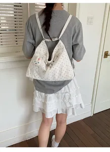 White polka dot tote bag worn as a backpack by a model in a casual lifestyle setting