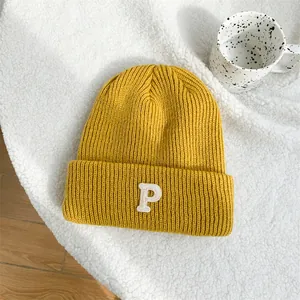 Detailed macro view of a vibrant yellow knit beanie featuring a white embroidered letter P